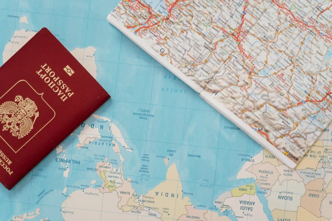 This image shows a close-up of an international travel setup, featuring an Italian passport, a map of Europe and parts of Africa, and a folded road map. It highlights travel preparations or planning, likely suitable for a blog article about international travel, travel tips, or exploration adventures.