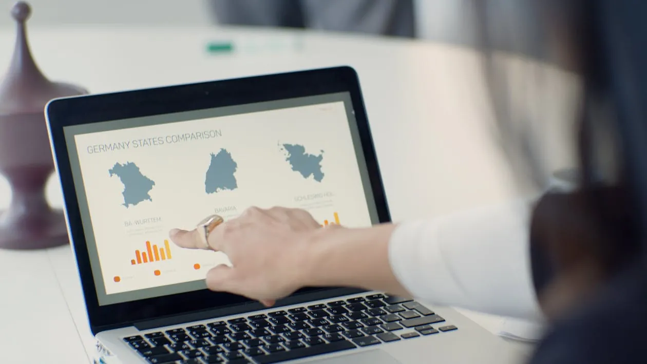 The image shows a person using a laptop to compare the states of Germany, with a focus on regional data and charts displayed on the screen, set in a modern, well-lit workspace. This photo would suit an article about data analysis, regional studies, or Germany-related statistics.