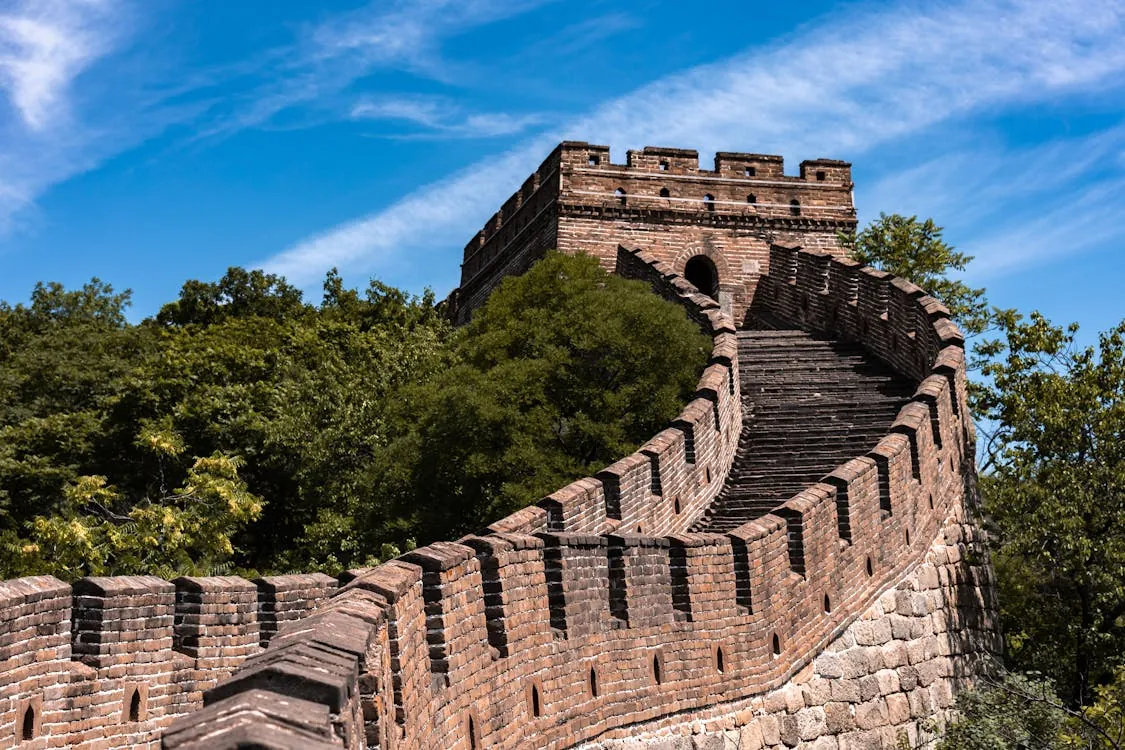 The Great Wall of China surrounded by lush greenery under a clear blue sky.