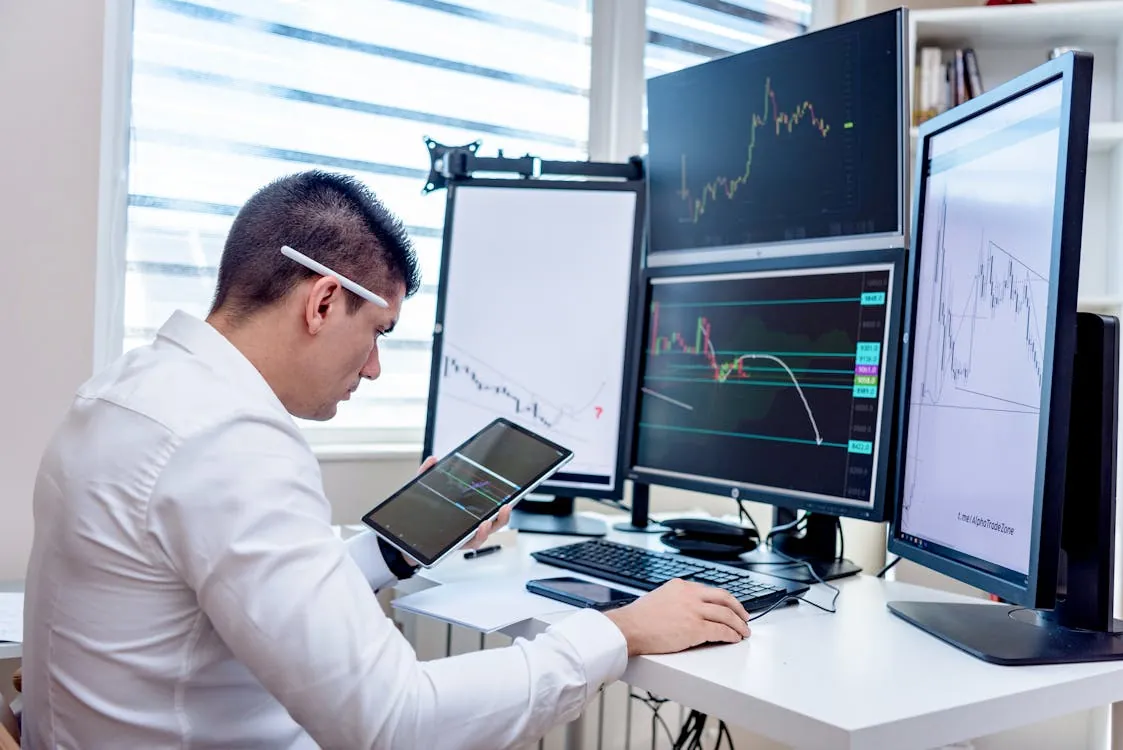 Investor reviewing stock charts and market data across multiple monitors
