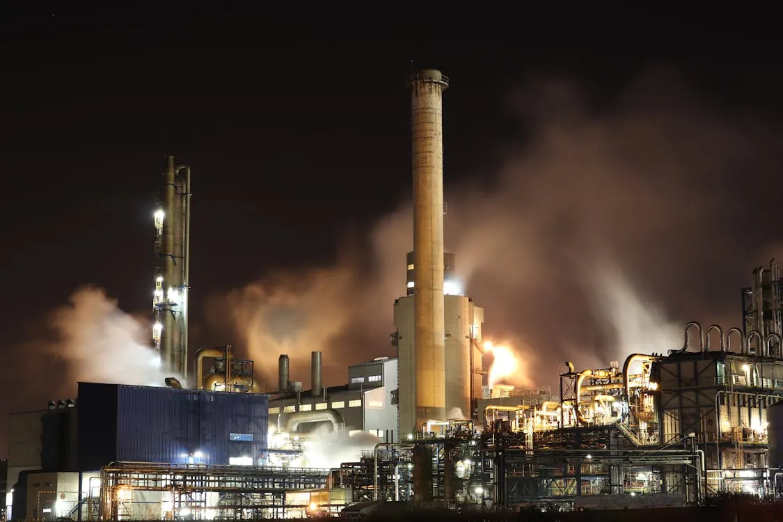 Industrial refinery at night with illuminated smokestacks and energy infrastructure