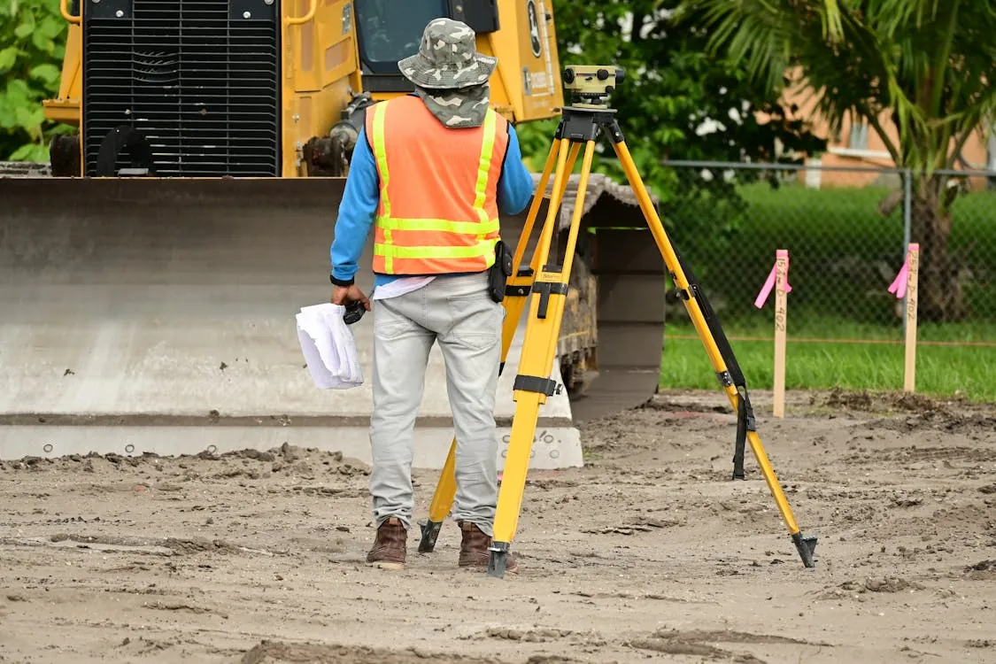 Survey worker using field equipment on a dirt site, representing exploration and land assessment