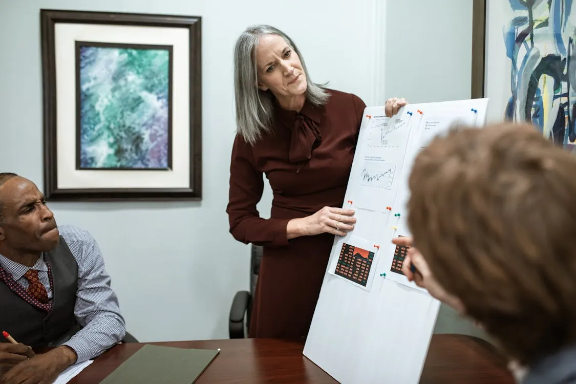 Businesswoman presenting data in a conference room meeting with colleagues.