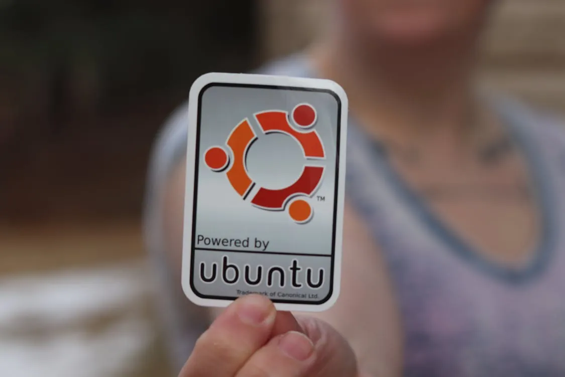 Person holding Ubuntu logo sticker