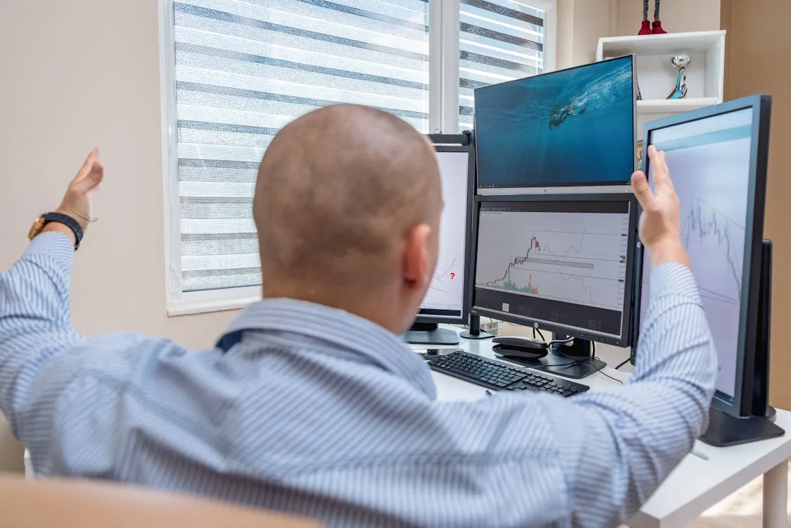 Trader at a desk with multiple monitors displaying stock charts