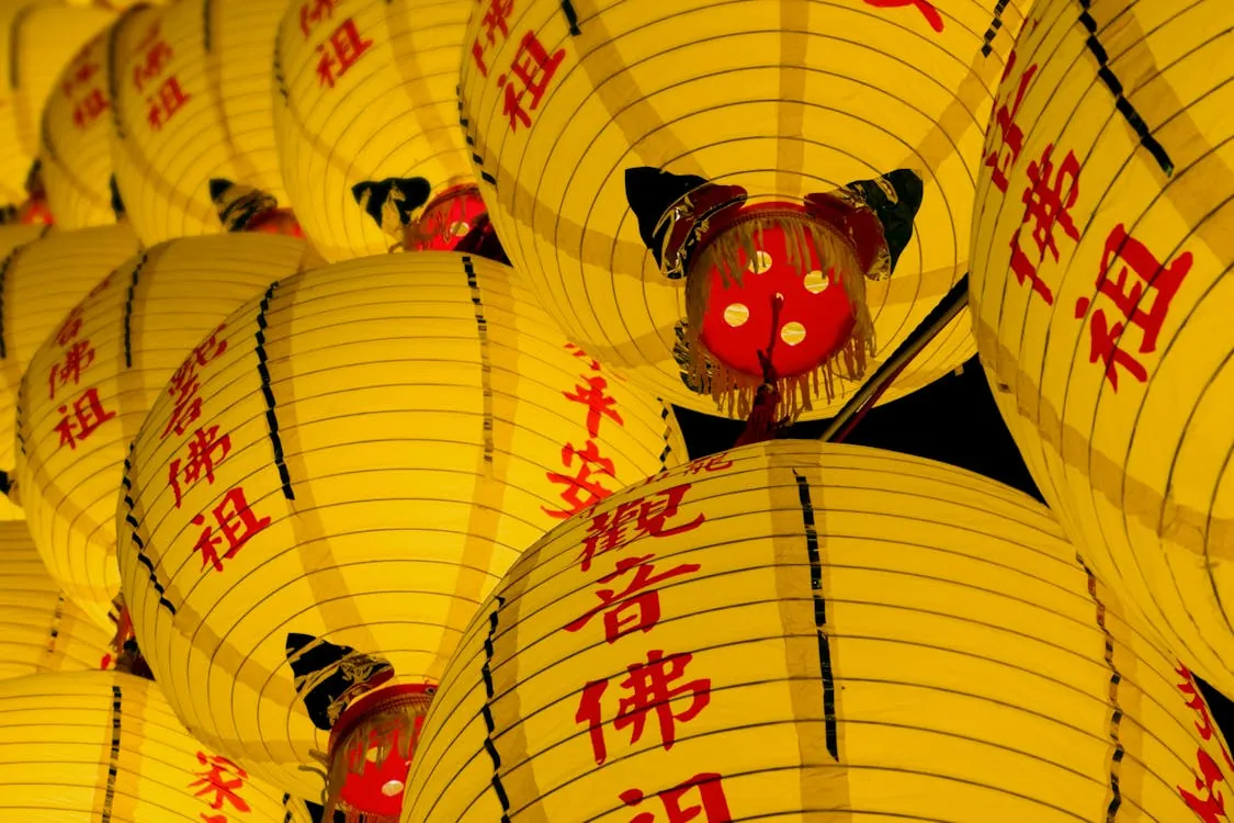 Bright yellow lanterns with red Chinese characters symbolize good fortune during the Lantern Festival celebration at night.