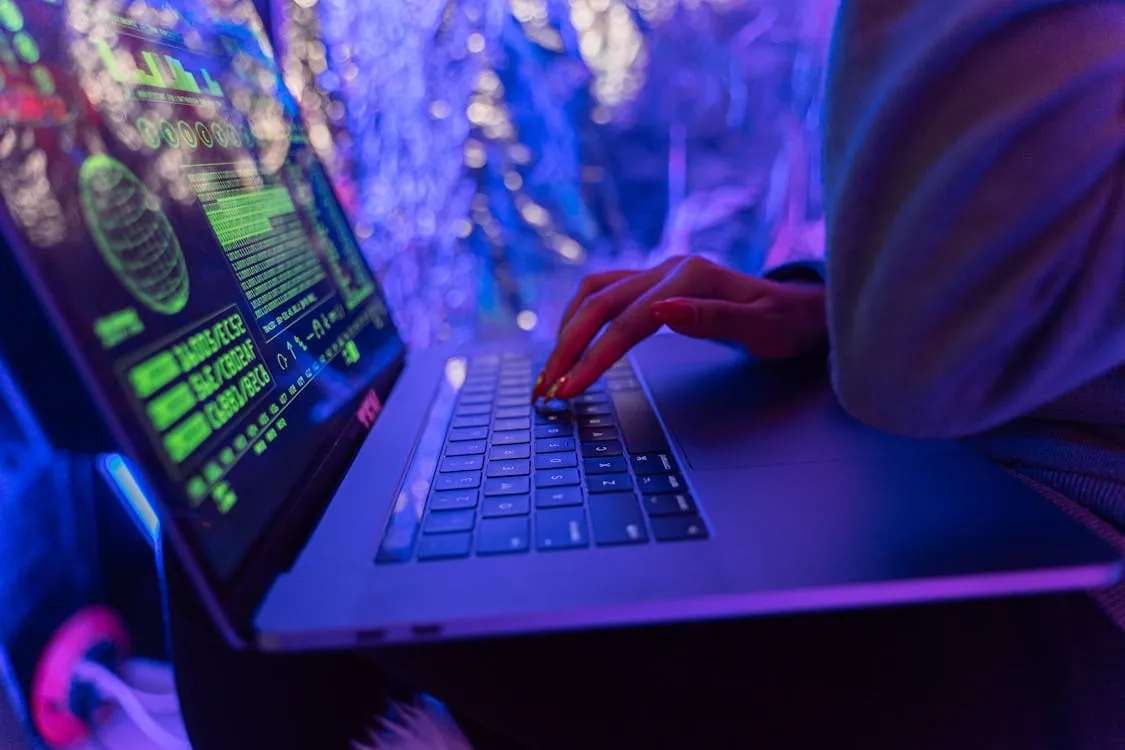 Close-up of hands typing on a laptop displaying cybersecurity graphics, representing the surge in phishing attacks and the importance of security awareness training in 2026.