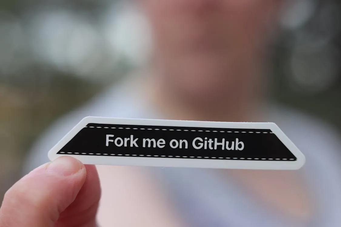 A hand holding a 'Fork me on GitHub' sticker, representing modern CI/CD pipelines with GitHub Actions and ArgoCD.