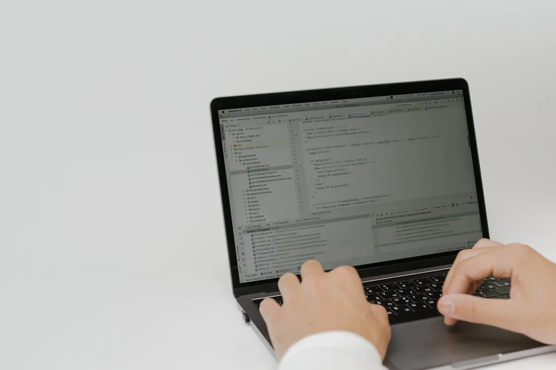 Hands typing code on a laptop in a workspace, representing Python programming tools and AI development.