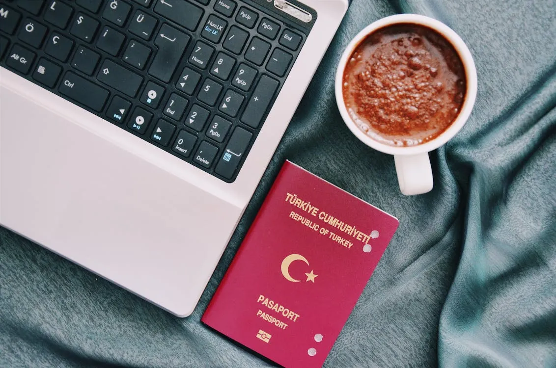 A Turkish passport beside a coffee cup and laptop, symbolizing the journey and process involved in residency and citizenship timelines.