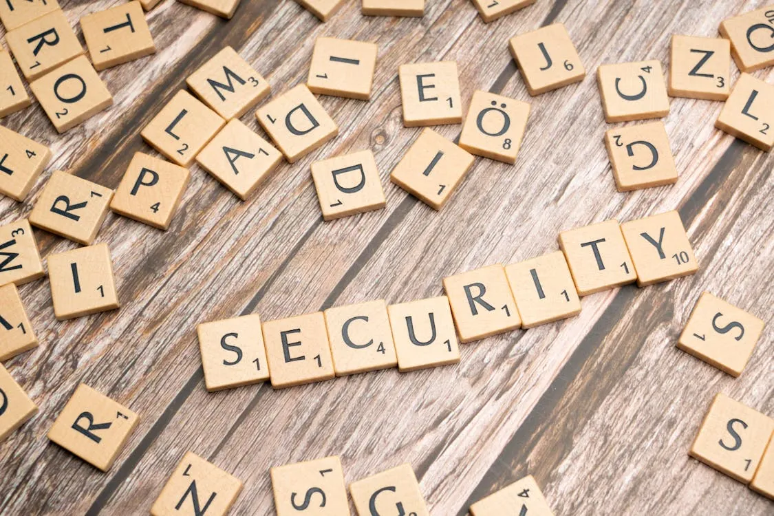 This image shows wooden Scrabble tiles arranged on a rustic wooden surface to spell out the word "SECURITY," with scattered tiles surrounding it. It is suitable for articles related to cybersecurity, data protection, or digital safety topics.