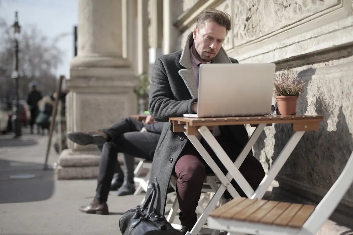 Man working on a laptop at an outdoor cafe representing city-based remote work abroad