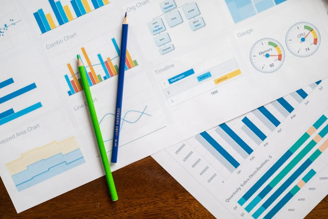 This image shows multiple sheets of data charts and graphs related to business analysis, featuring bar charts, line graphs, and gauge indicators with colorful pencils placed on top. It would be suitable for articles about data analytics, business performance, or financial reporting.