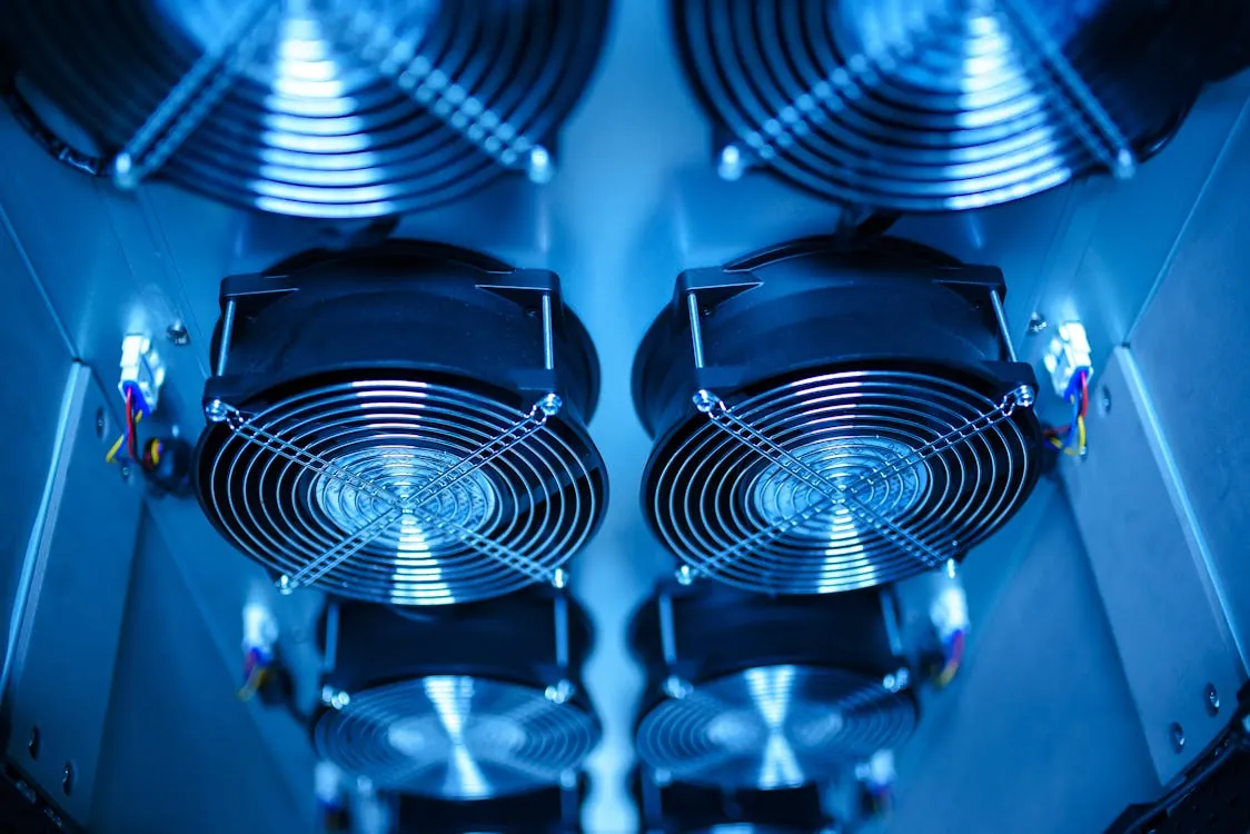 This photo shows a close-up view of multiple industrial cooling fans inside a server or data center equipment, illuminated with blue lighting. It highlights the technical and cooling components essential for maintaining optimal operation in high-tech environments, suitable for articles on data center infrastructure or cooling technology.