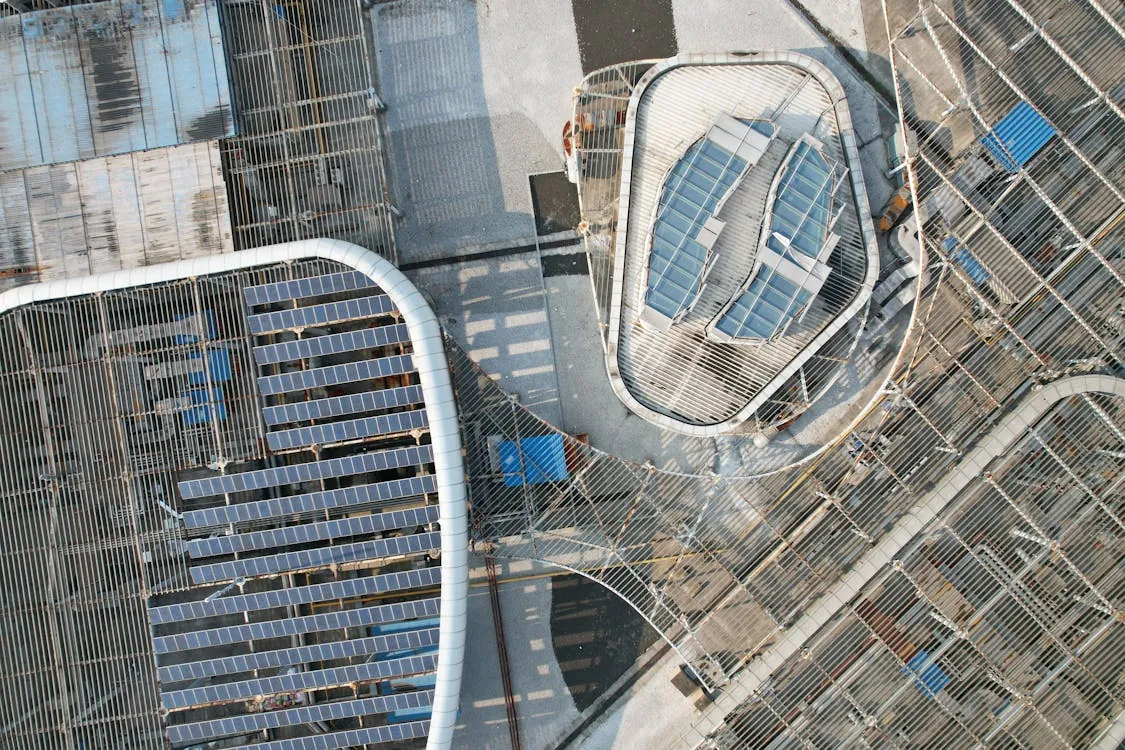 This aerial photo shows a modern building roof equipped with numerous solar panels, emphasizing sustainable architecture and renewable energy sources in an urban setting. The image highlights the integration of solar technology into city infrastructure, suitable for articles discussing green urban development or renewable energy initiatives.