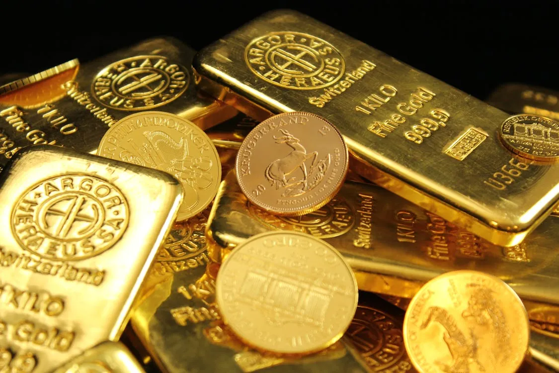 Gold bars and commodity trading screens representing oil and metals markets