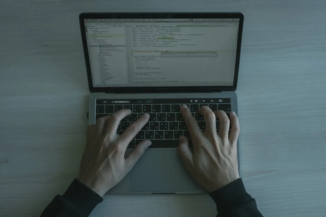 Developer typing on a laptop with code on screen