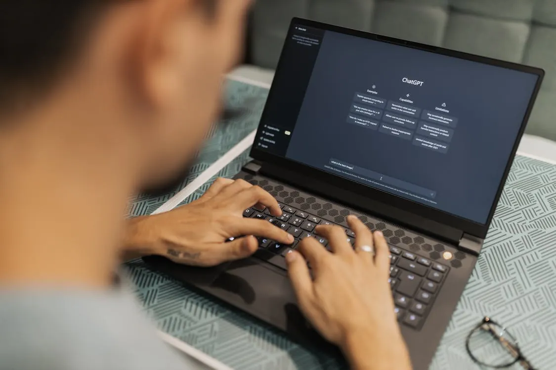 A developer using a laptop with an AI chat interface on screen