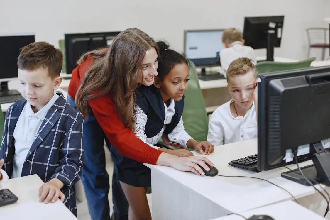Teacher helping students at computers in a classroom
