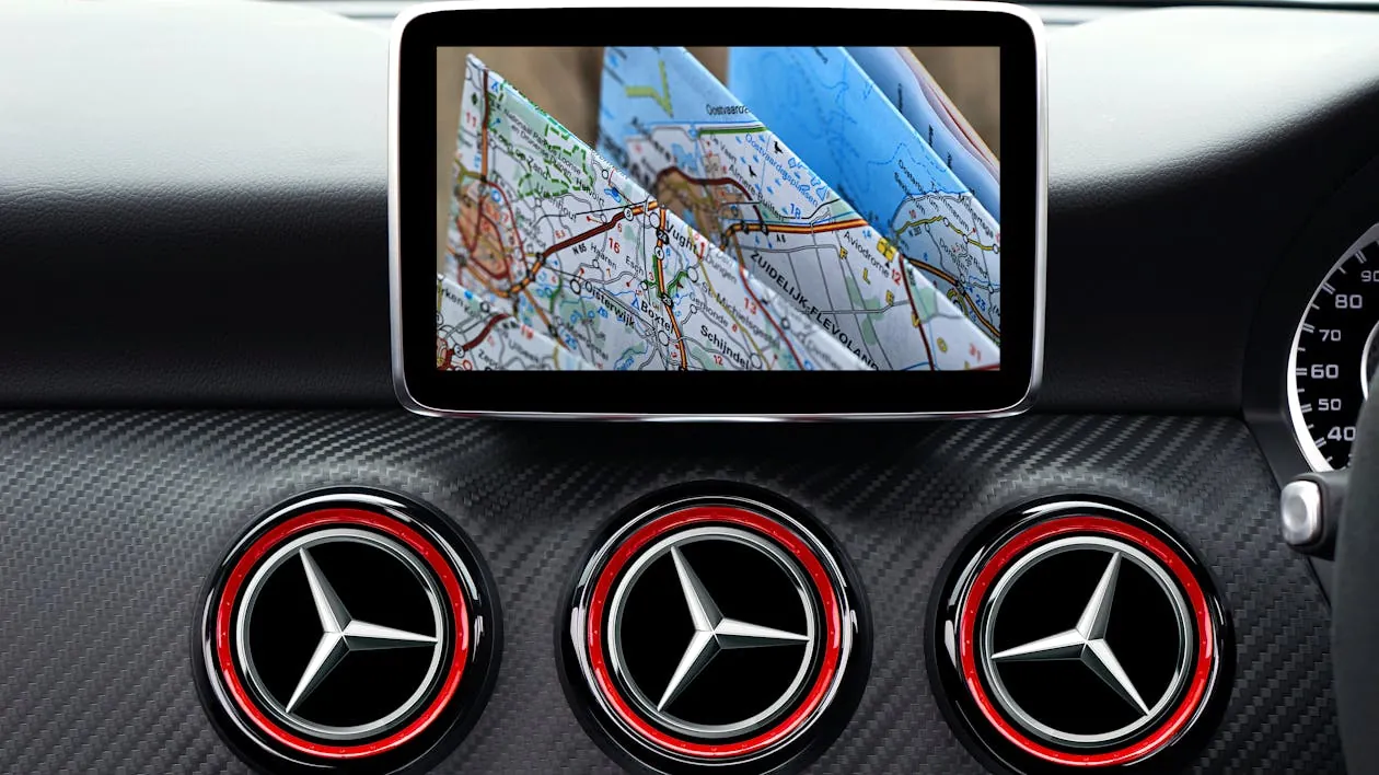 This image shows the interior dashboard of a car with a focus on three circular air vents featuring the Mercedes-Benz logo, and a mounted digital navigation screen displaying a detailed map with routes and geographic labels. It highlights modern automotive technology and luxury design, suitable for articles about car interiors, navigation systems, or luxury vehicle features.