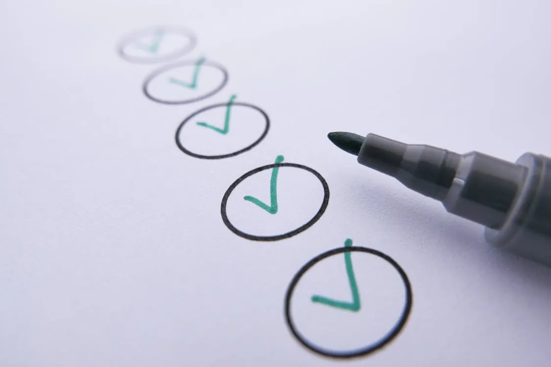 This image shows a close-up of a checklist with five circles, each containing a green checkmark, and a black marker pen resting nearby. The setting appears to be on white paper, making it suitable for articles about task completion, organization, productivity, or goal-setting.