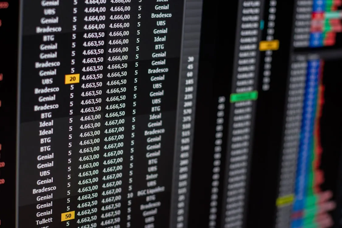 This image shows a close-up of a digital stock market screen displaying various stock data, including company names, prices, and volume. It appears to be taken in a financial setting such as a trading floor or an office, with highlighted numbers indicating specific stock activity.