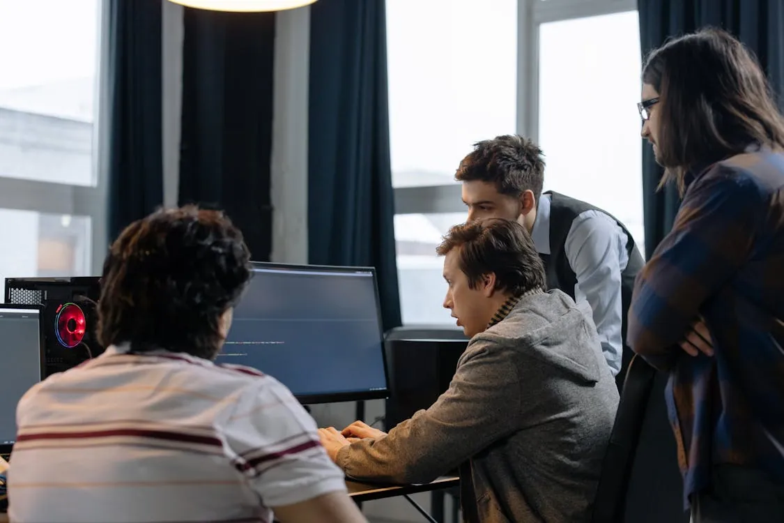 Group of developers working together on a computer programming project, collaborating on workflows and code examples.
