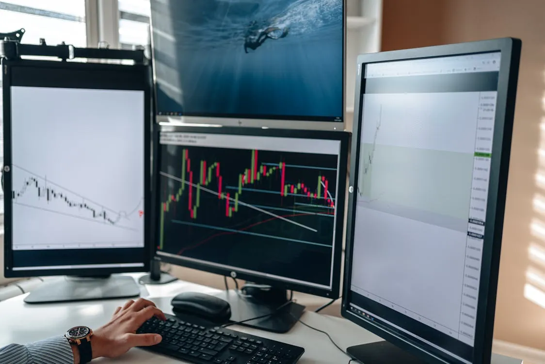Trading desk monitors showing financial market charts and price movements