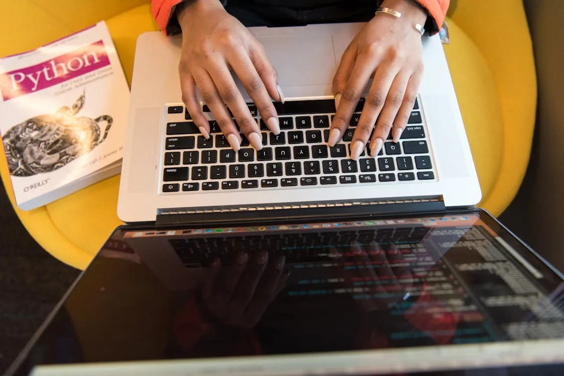 Person coding Python on laptop