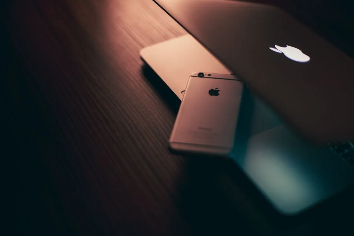 Apple MacBook and iPhone on office desk representing enterprise device fleet