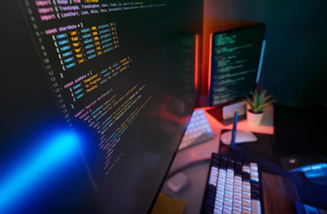 Developer working on modern desktop computer setup with multiple monitors in well-lit workspace