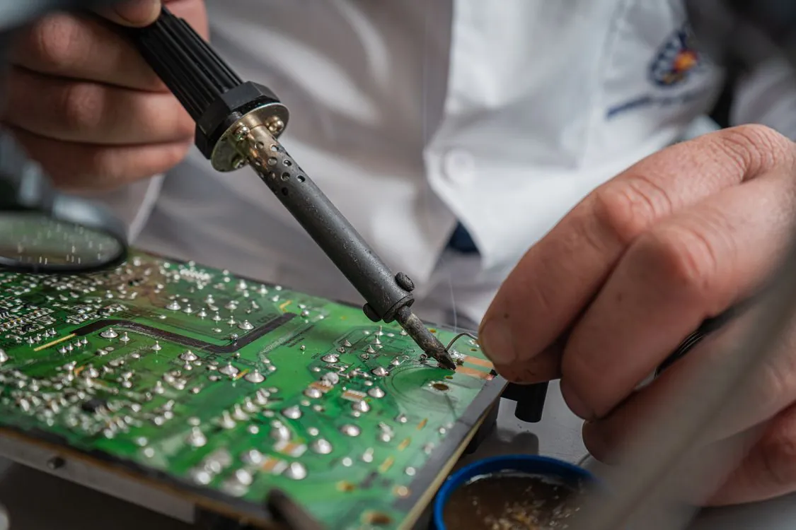 Technician performing precise soldering on circuit board