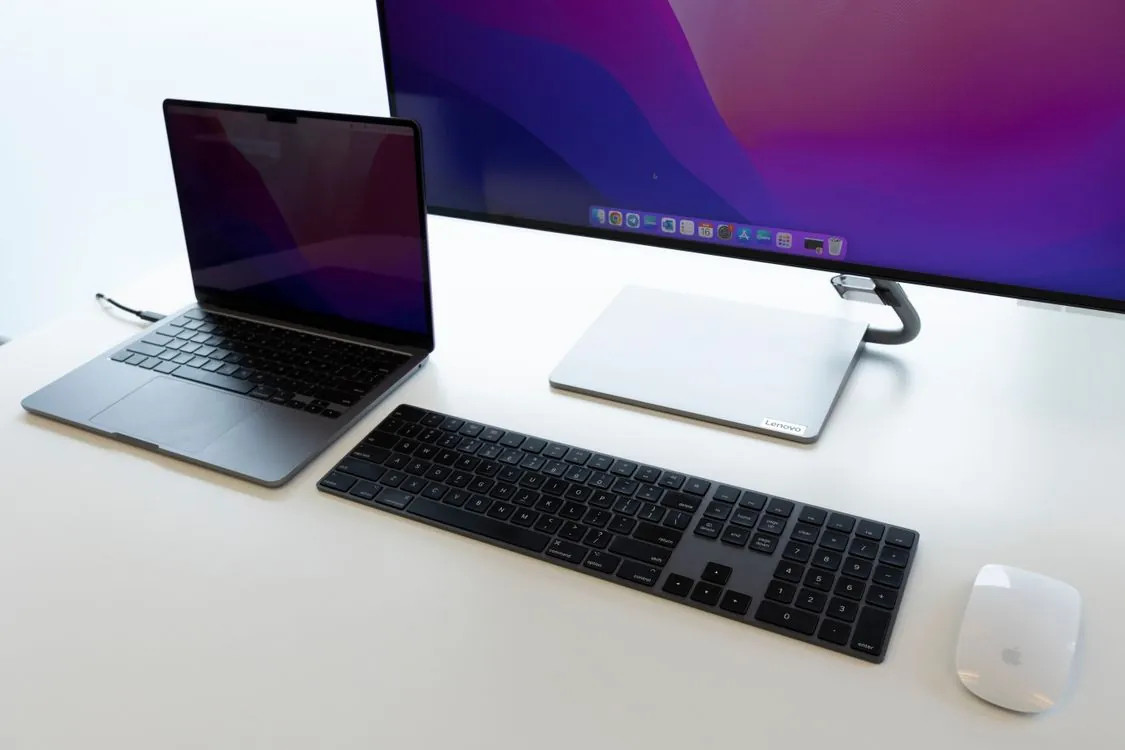 MacBook on desk in modern office with IT management dashboard visible on screen