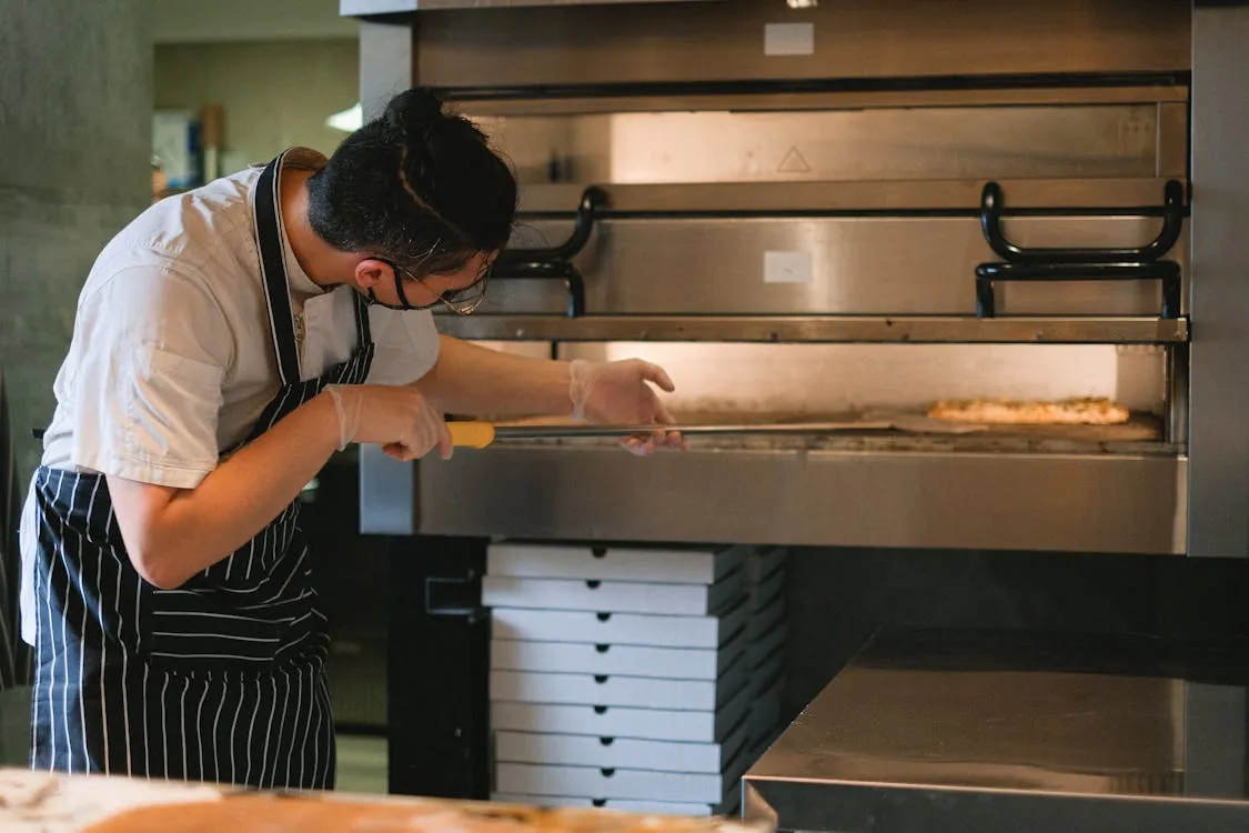 Pizza being prepared in commercial kitchen