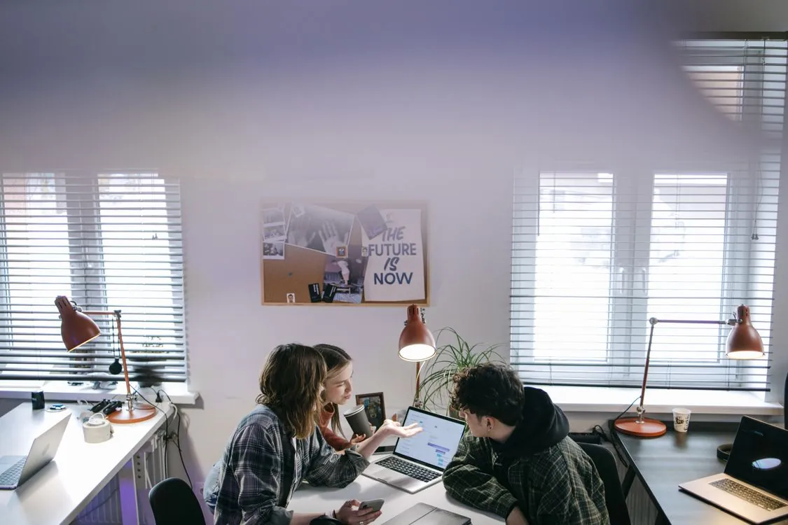 Small team collaborating with Mac laptops in modern office