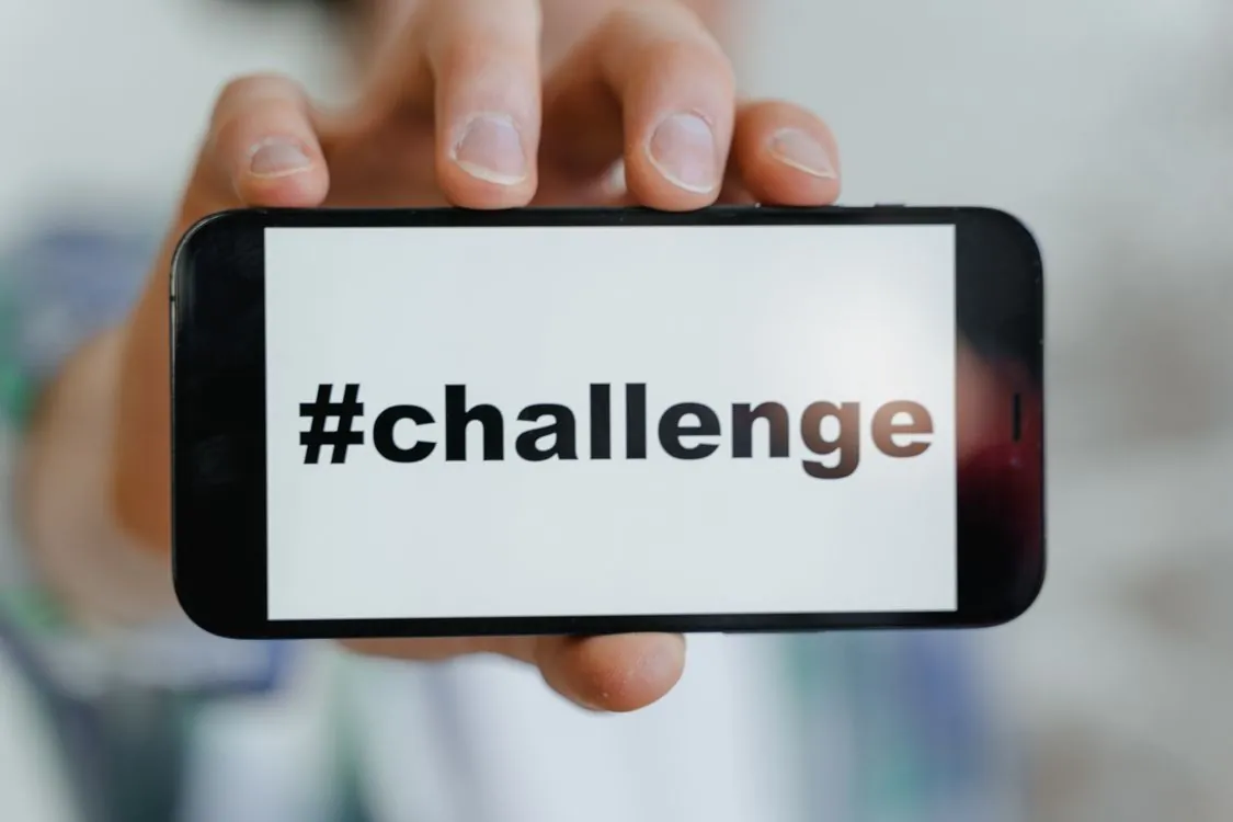 Person holding smartphone with social media feed showing trending hashtags