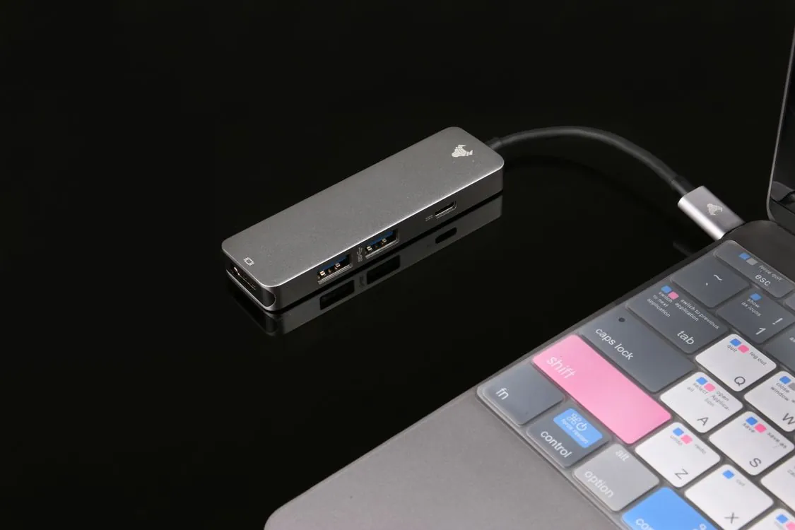 A person plugging a USB cable into a powered USB hub with multiple devices connected