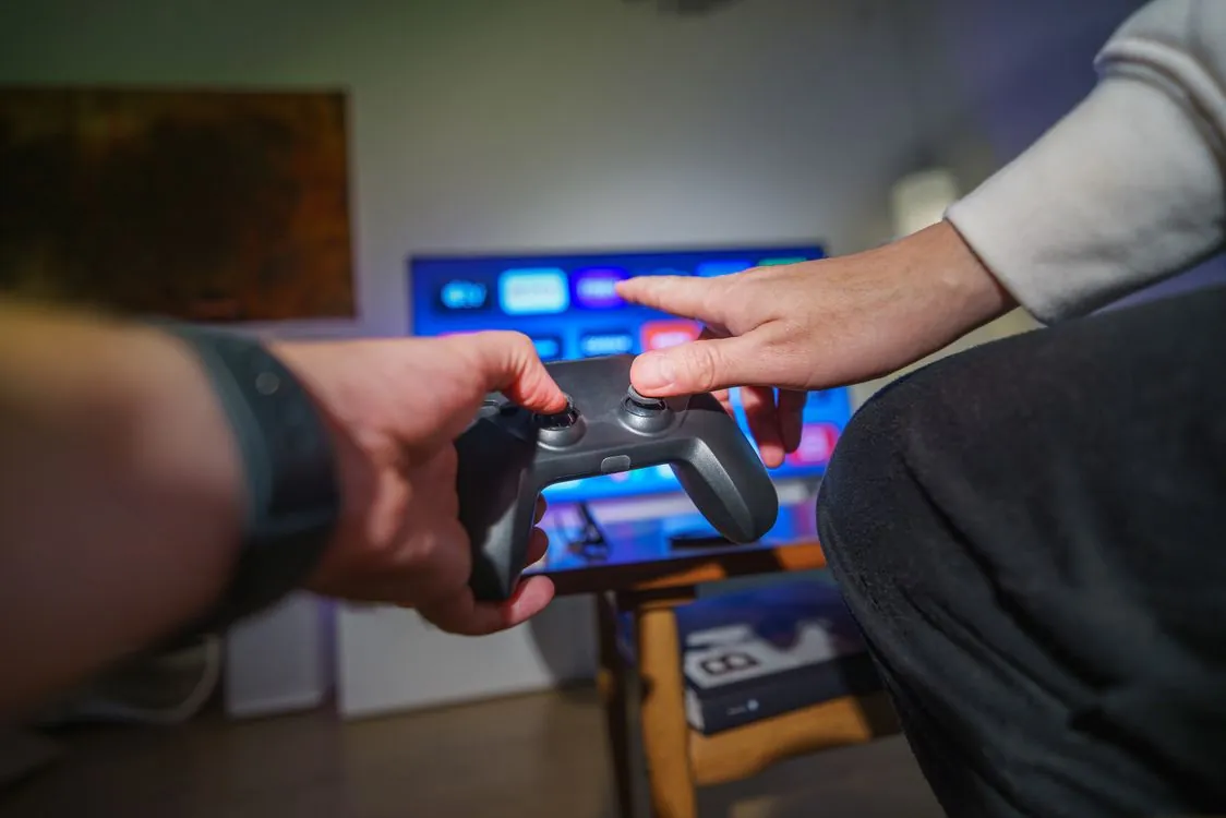 Person playing video game on television with controller
