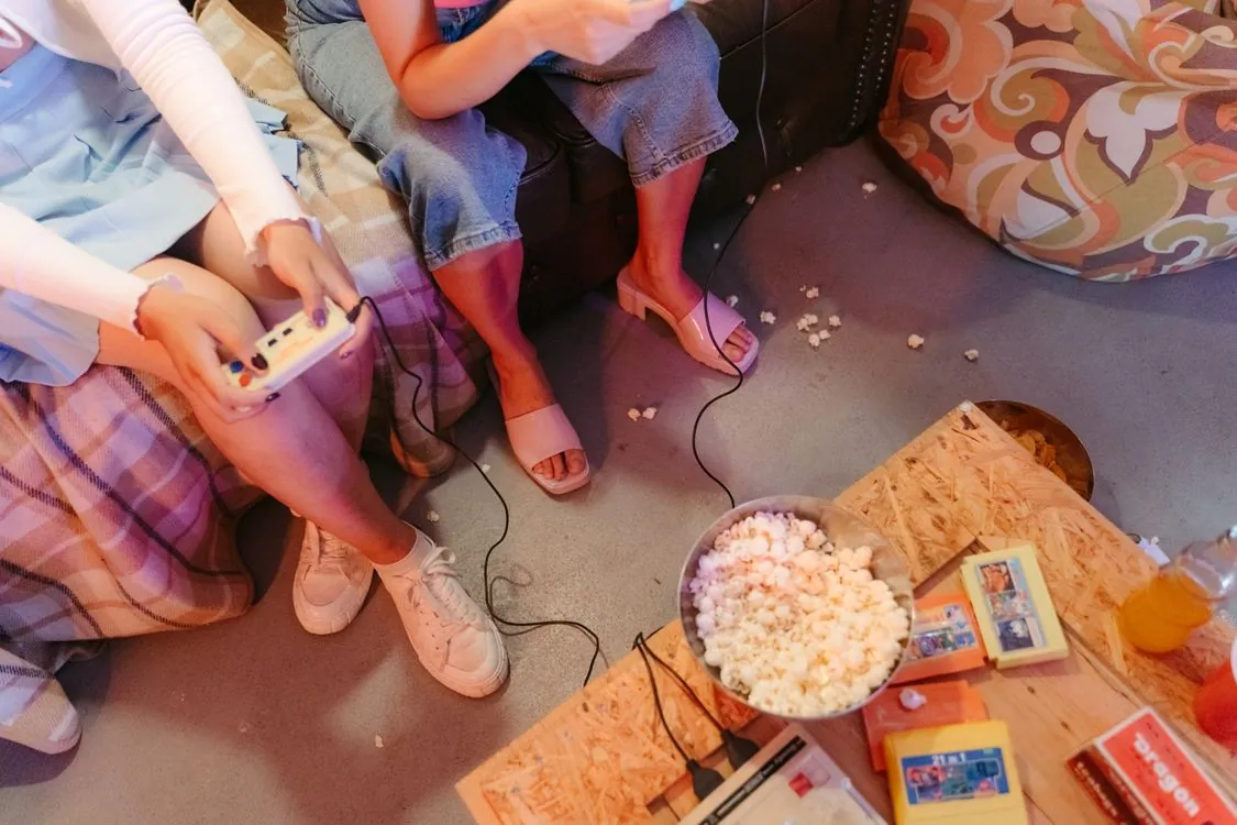 Two people playing retro video games together on a couch