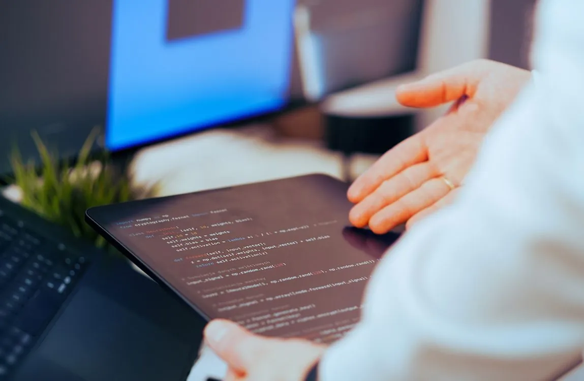 Software developer working with AI coding assistant on multiple displays