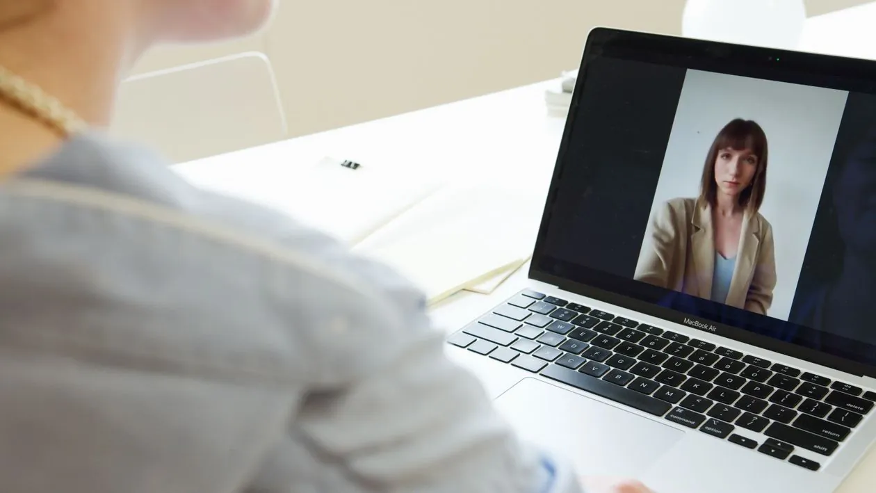 Woman on video call using laptop in modern workspace