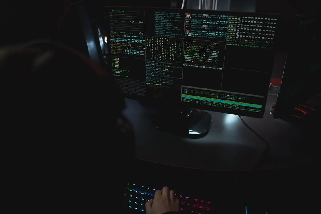 Code displayed across monitors in a cybersecurity workspace