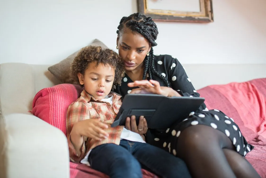 A parent and child looking at tablet together