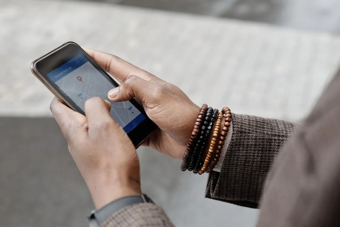 Hands holding a smartphone with a map app while surveying a street