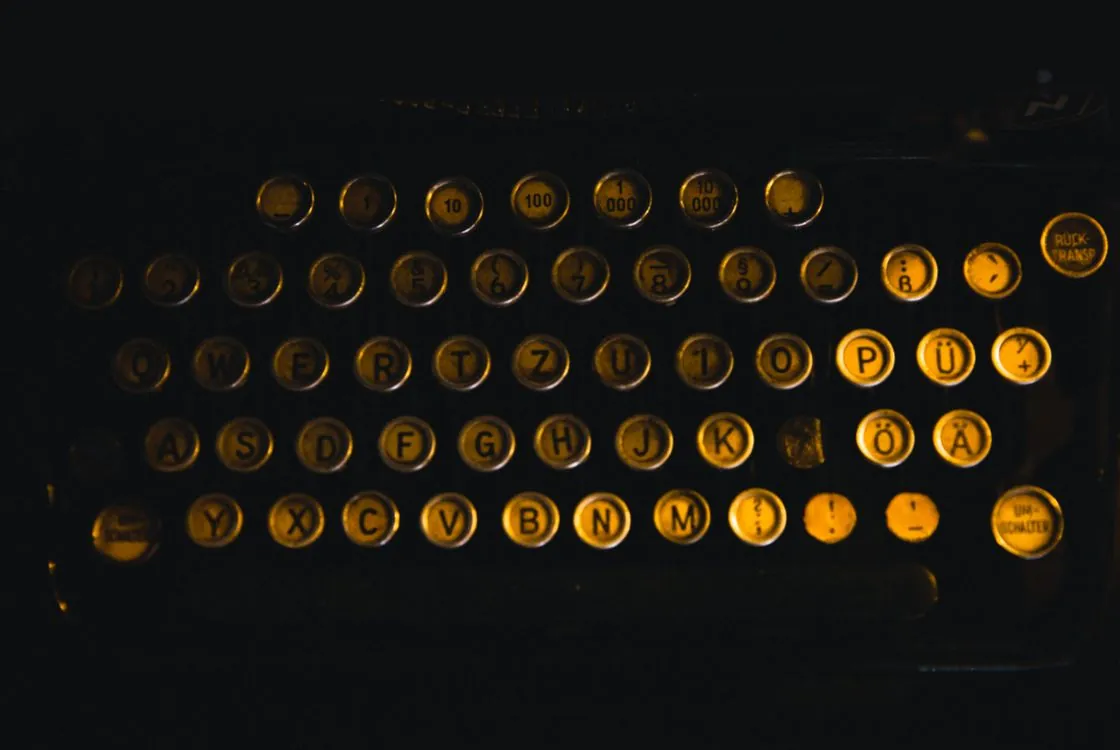 Close-up of vintage typewriter keys with German letters in low light, evoking WWII German Enigma cipher machines