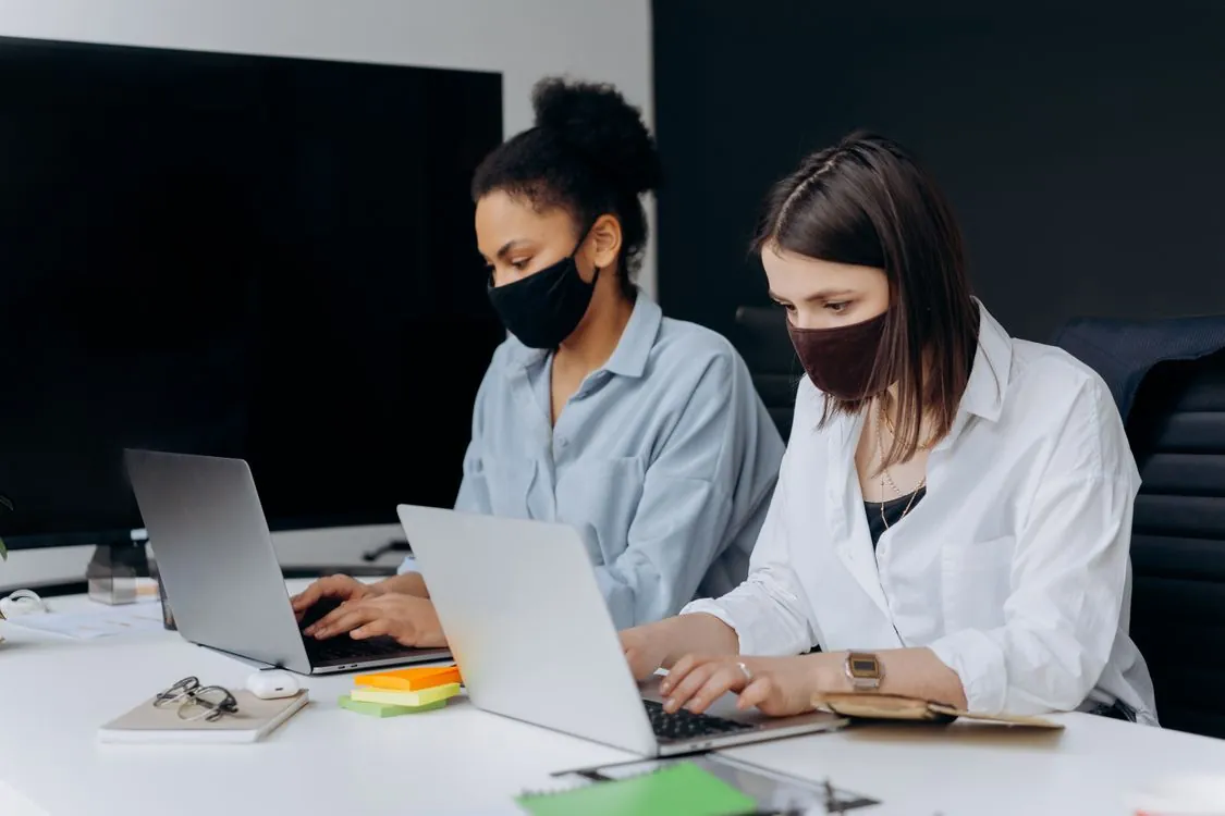 Distributed team working across laptops and mobile devices in a hybrid office