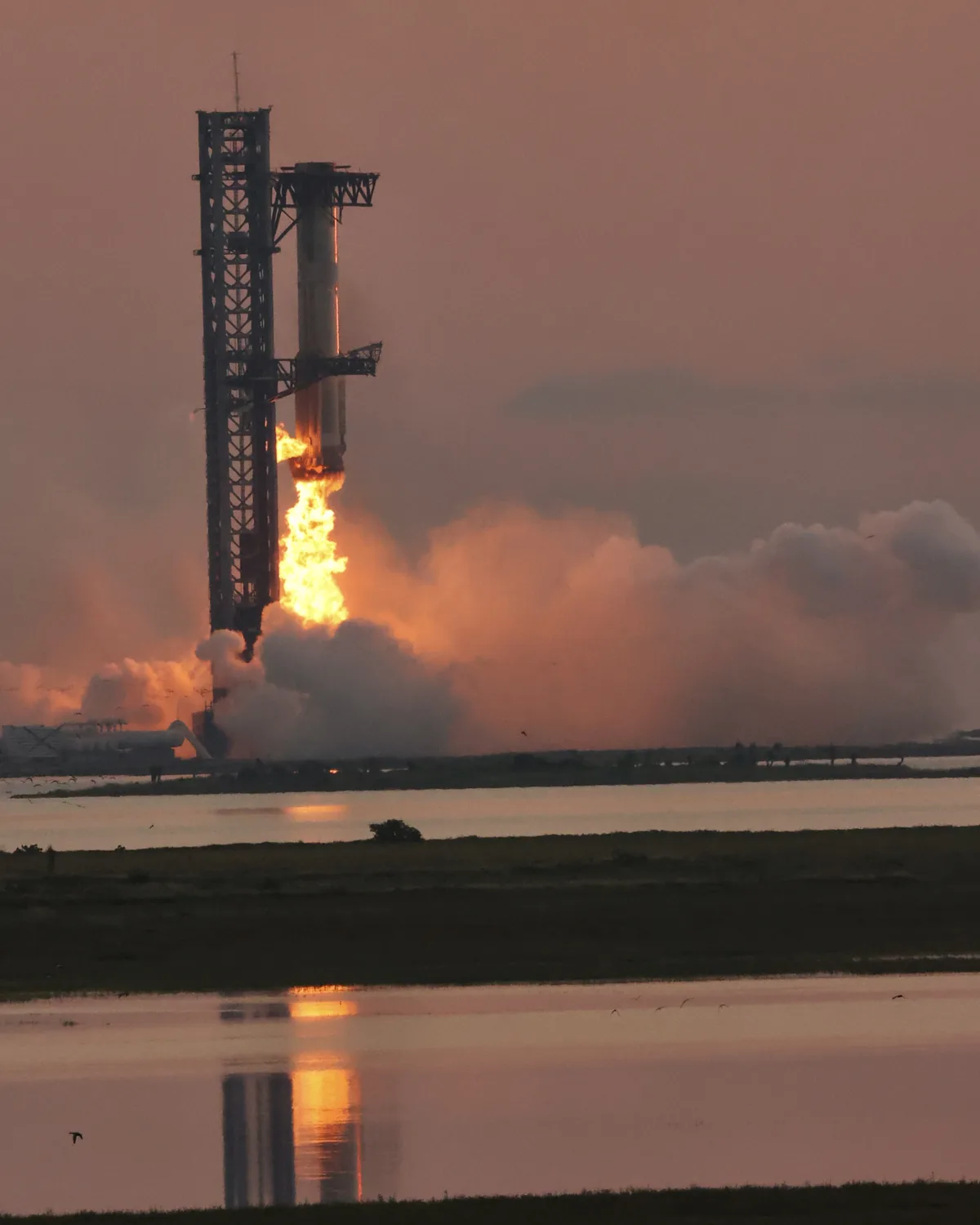 Super Heavy booster firing its engines as the launch tower's arms catch it at Starbase during Starship Flight 5, October 13, 2024.